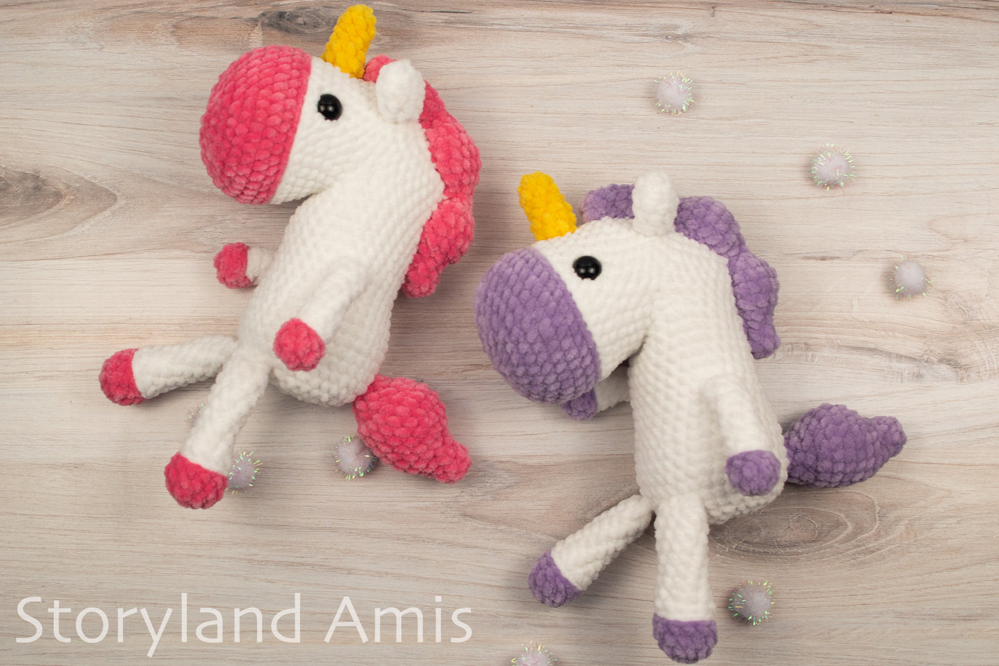Two crocheted unicorn toys on a wooden surface with 'Storyland Amis' branding.
