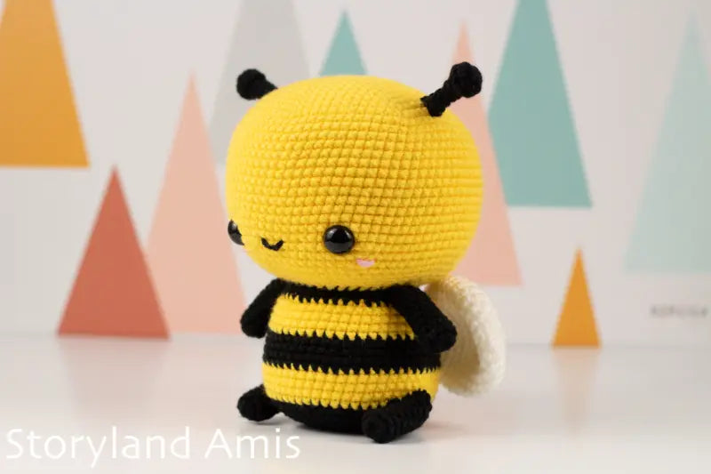 Crocheted bee toy with a colorful geometric background