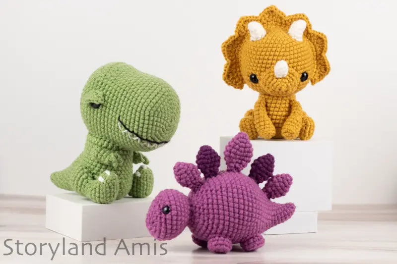 Three crocheted dinosaur toys in green, yellow, and purple on a white background with 'Storyland Amis' branding.