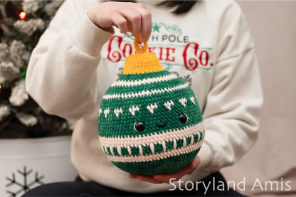 Person holding a green crochet ornament with a yellow top, wearing a Christmas-themed sweater.